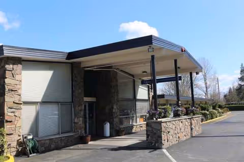 Exterior view of Redmond Care and Rehabilitation Center entrance with stone facade and canopy.