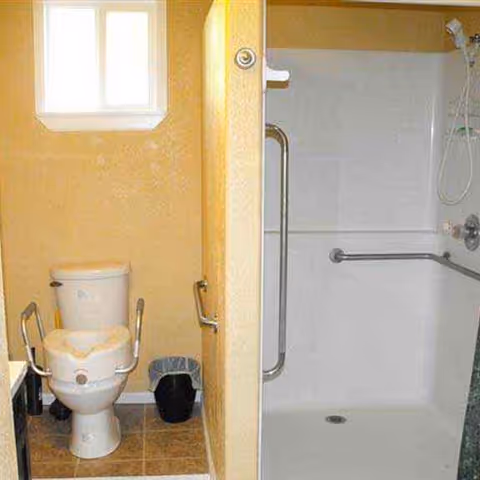Accessible bathroom with toilet, grab bars, and a walk-in shower.