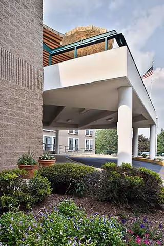 Exterior view of a senior living facility entrance with a covered drop-off and landscaping.