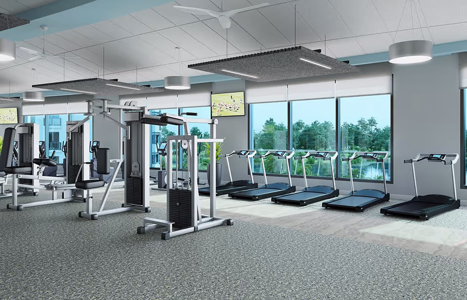 Bright fitness center with treadmills and strength machines facing large windows overlooking greenery.