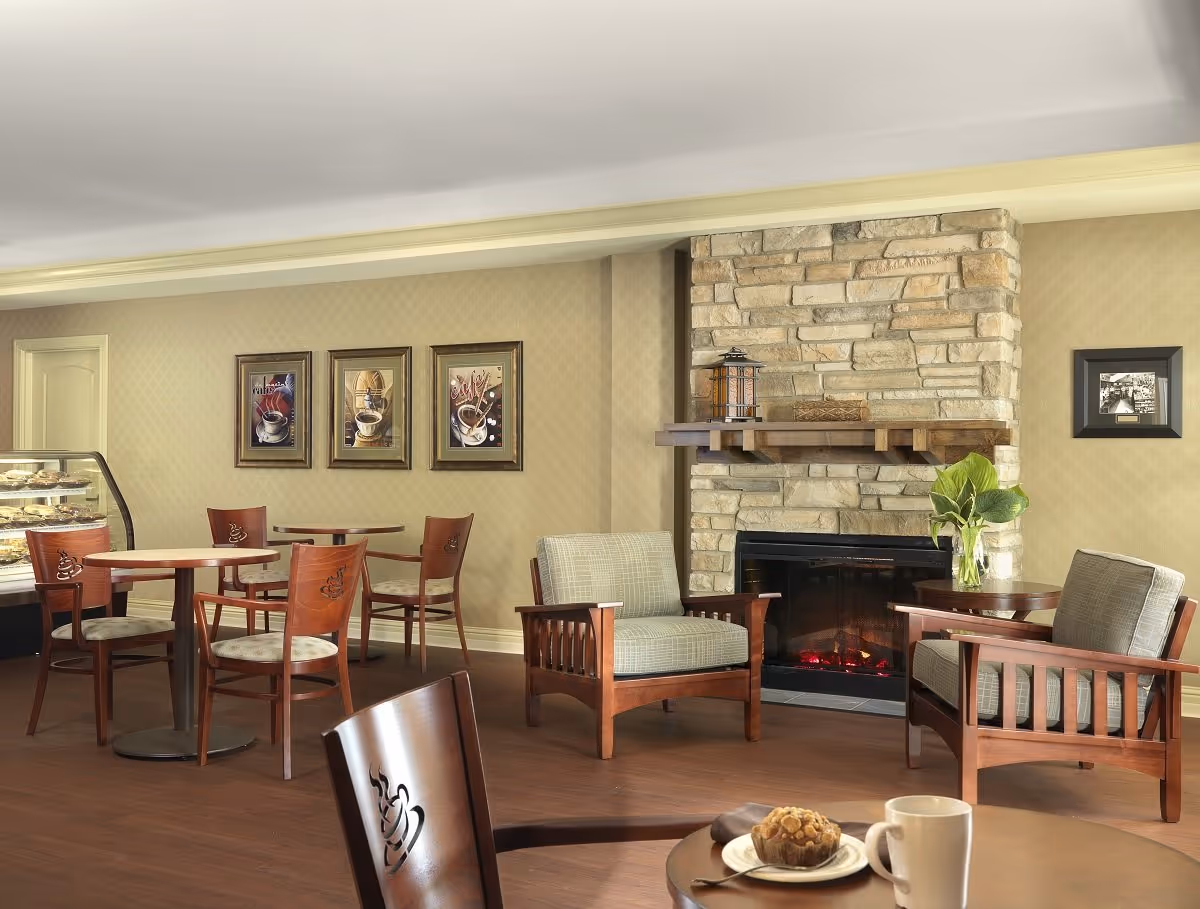 Cozy common dining area with tables, chairs, a pastry display case and a stone fireplace.
