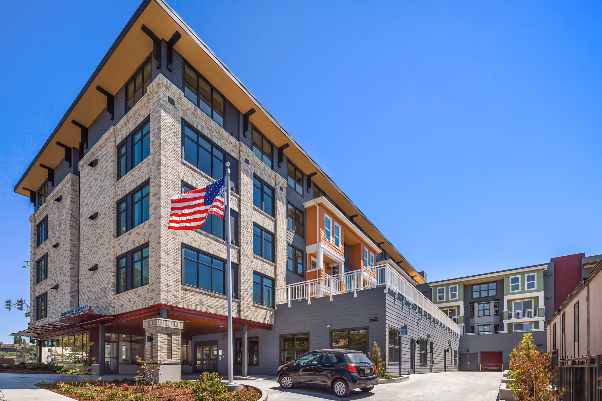 Exterior view of Merrill Gardens at Rockridge building with an American flag in front.