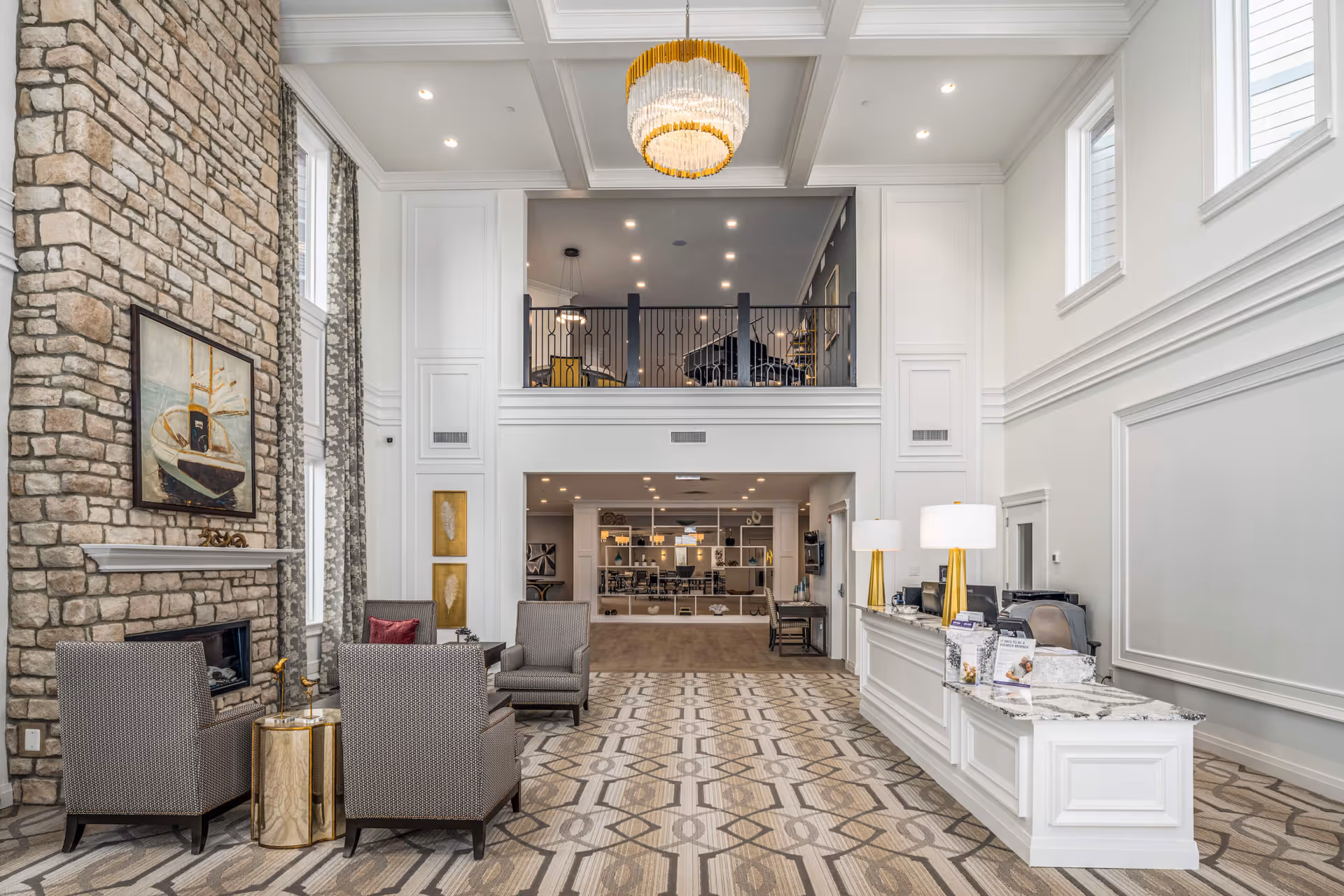 Spacious two-story reception lobby with seating area, stone fireplace, chandelier, and a front desk.