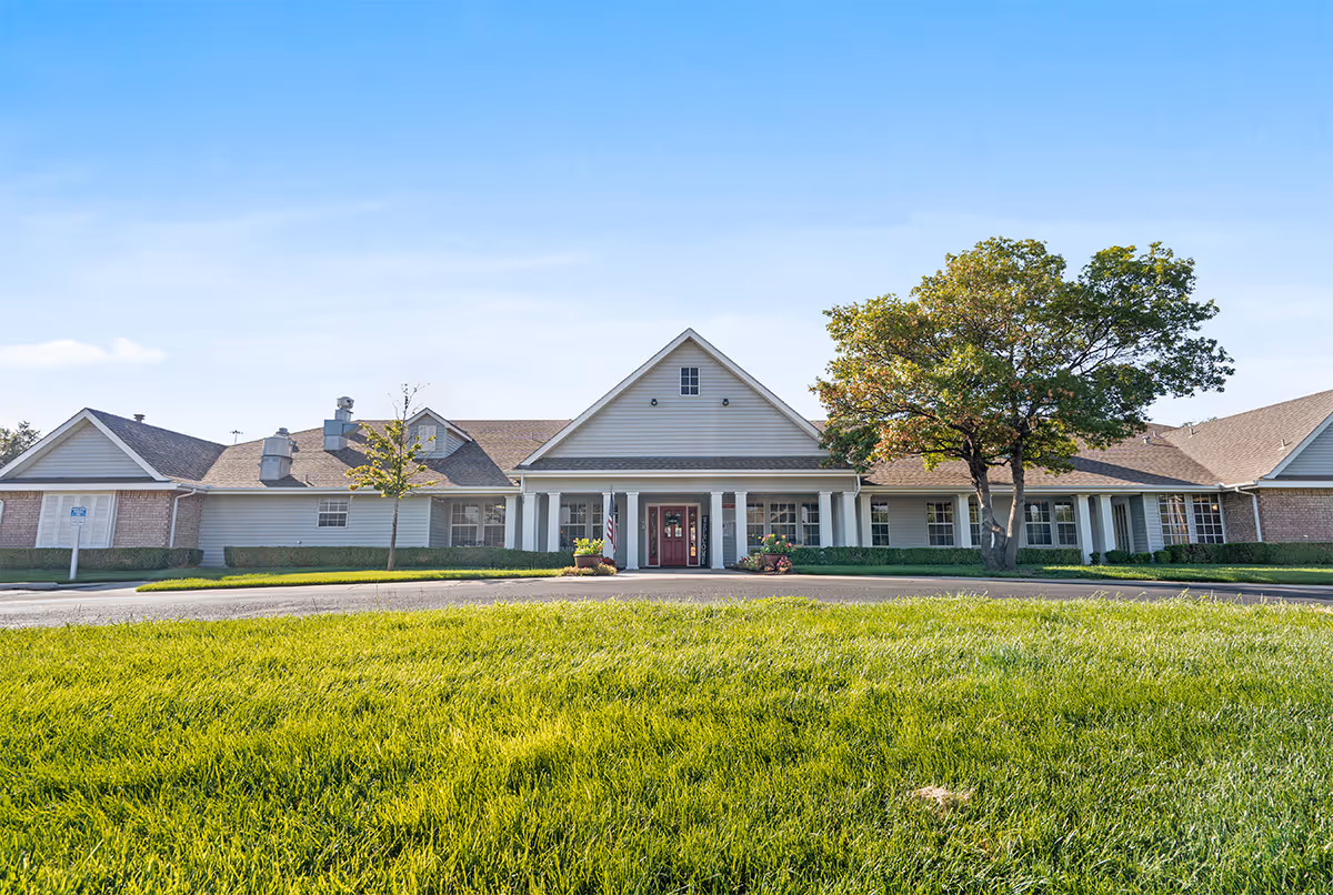 Front view of a single-story senior living facility with a manicured lawn and entrance.