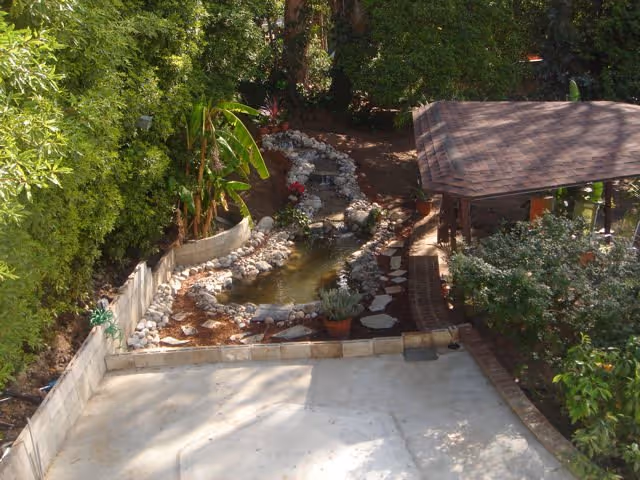 Aerial view of a garden pond with rocks, trees, and a gazebo.