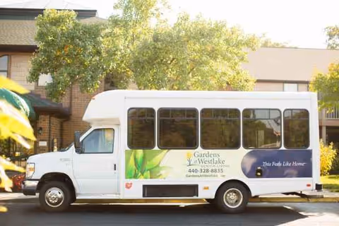 A white shuttle bus with Brookdale Gardens at Westlake parked outside a brick senior living facility.