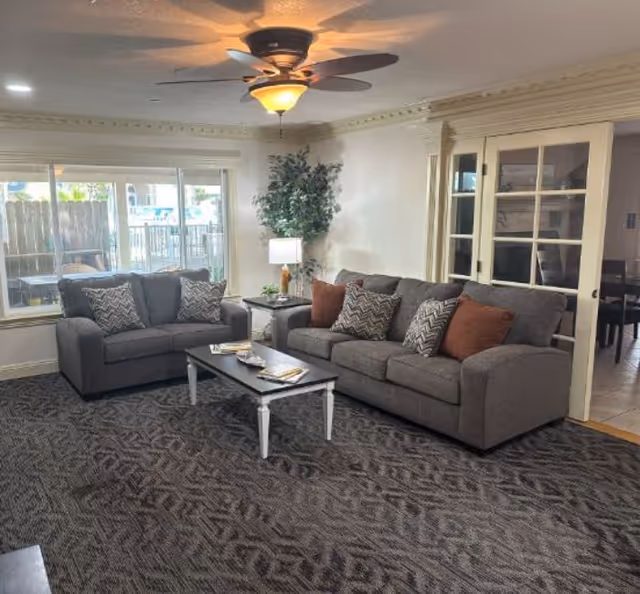 Cozy senior living room with two gray couches, a coffee table, and a ceiling fan.