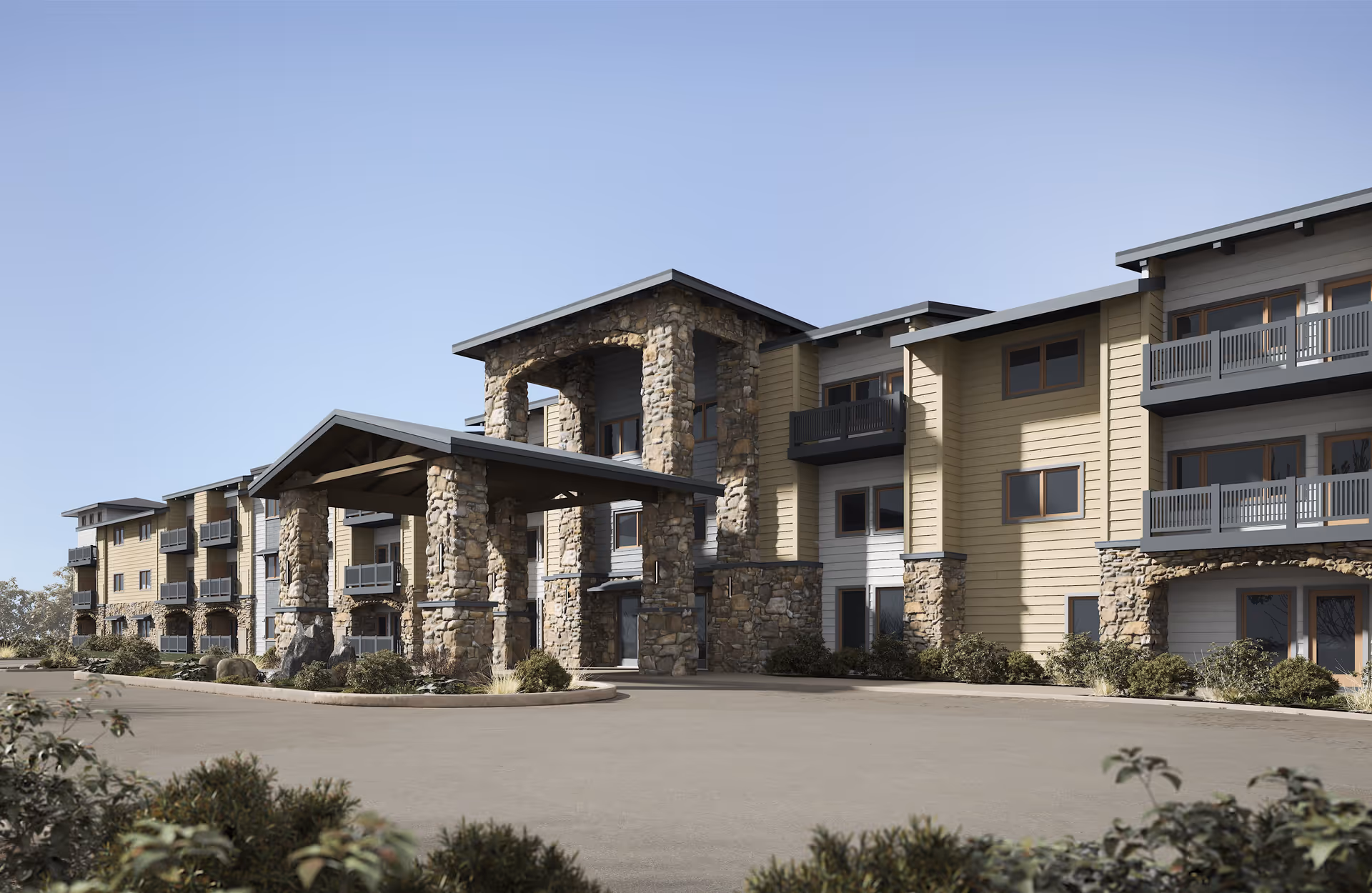 Exterior view of Hearthstone Lodge Senior Residences showing a multi-story building with stone pillars and balconies under a clear blue sky.