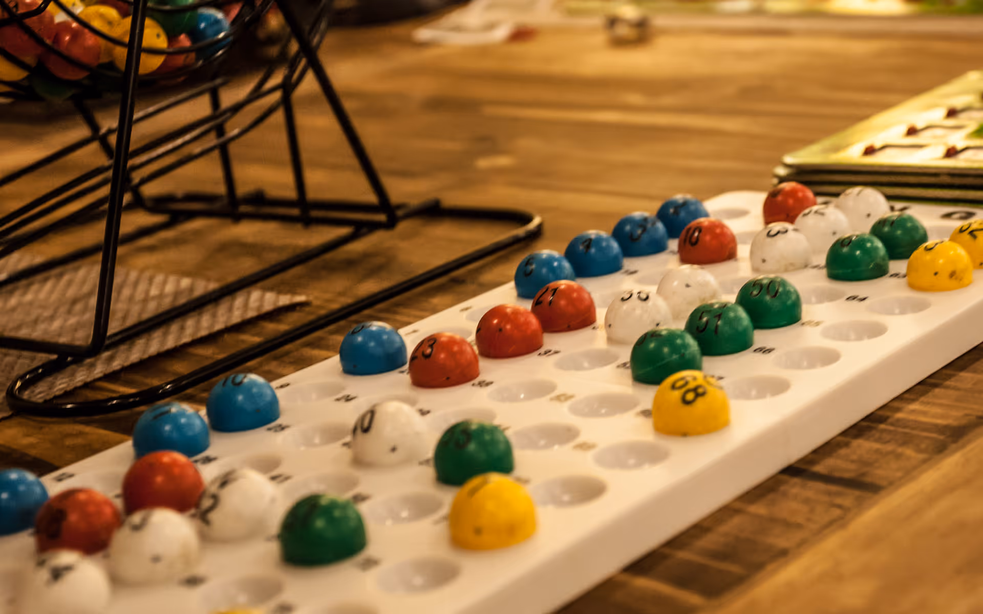 Close-up of a bingo number board with colored numbered balls arranged on a wooden table.