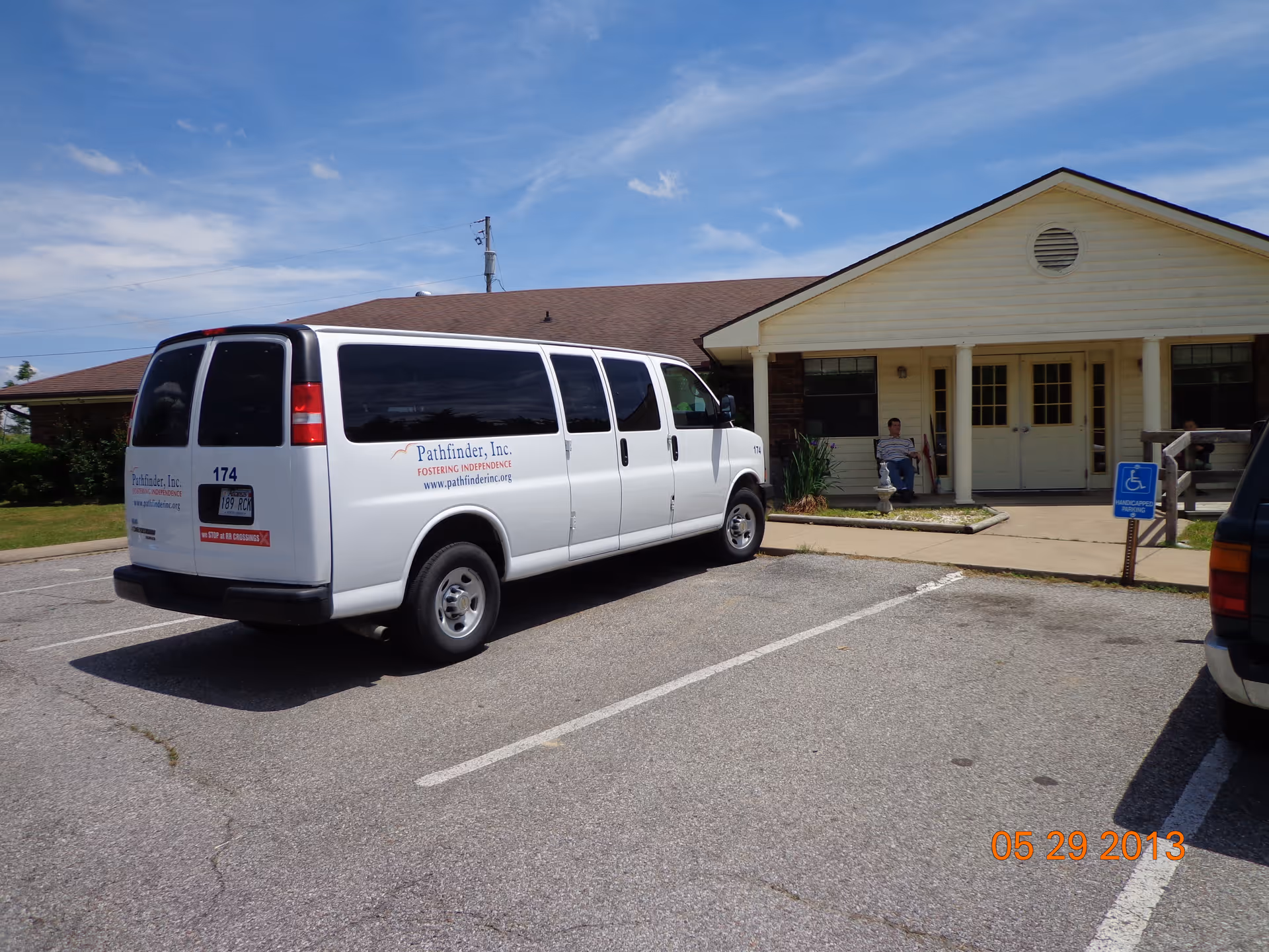 White Pathfinder, Inc. van parked in front of a single-story facility entrance with a person sitting on the porch.