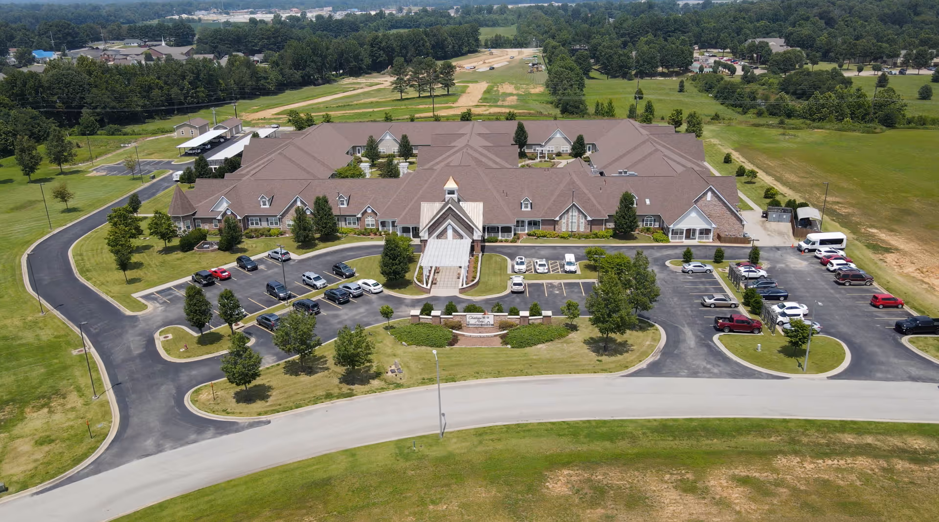 Aerial view of Chateau On the Ridge senior living facility showing the single-story building with a central entrance canopy, surrounding parking lots and lawns.
