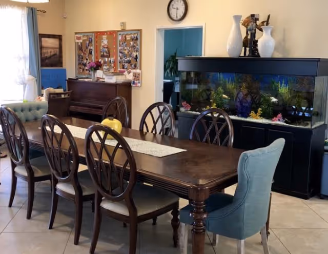 A dining room with a long wooden table, chairs, aquarium, and bulletin boards.