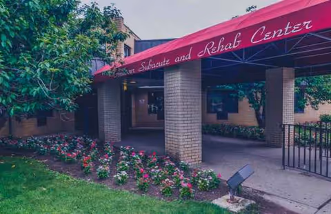 Entrance of Andover Subacute and Rehab Center with brick columns and blooming flowerbeds.