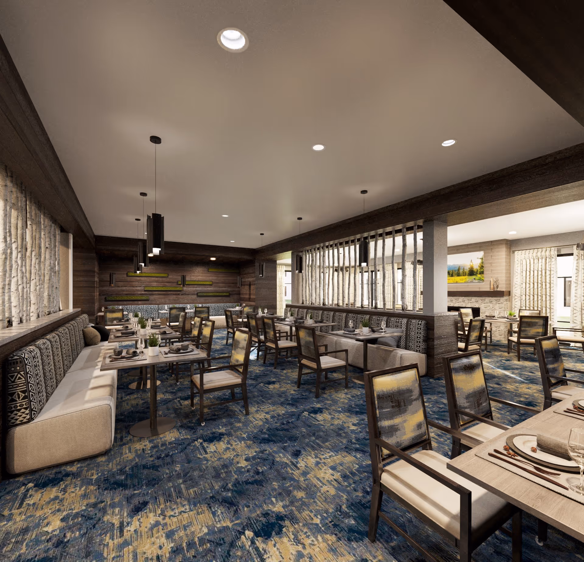 A spacious dining room with multiple tables and chairs arranged neatly. The room features patterned carpet in shades of blue and beige, cushioned bench seating along the walls with decorative pillows, and modern pendant lighting hanging from the ceiling. The walls have wood paneling and artistic decor, with large windows allowing natural light to enter.