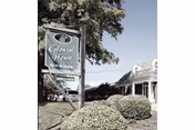 Sign for Colonial House Senior Living by a white building entrance with shrubs