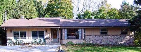 Exterior single-story building with stone accents and plastic chairs on a front patio.