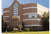 Brick senior living facility with arched front window and landscaped lawn.