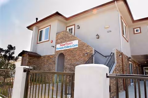 Exterior view of Ramona Senior Manor with stone entry, stairs, and 'Now Open' sign.