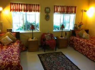 Two twin beds with red patterned spreads flank nightstands and lamps in a cozy bedroom.