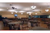 Large dining room with multiple tables and chairs under ceiling fans and chandeliers.