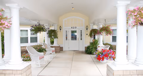 Covered entrance/portico with white columns, chairs, hanging flower baskets, and double doors numbered 420.