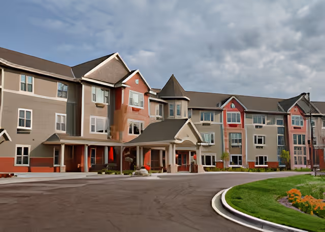 Front exterior of a multi-story senior living facility with a covered entrance, circular driveway, and landscaped lawn.