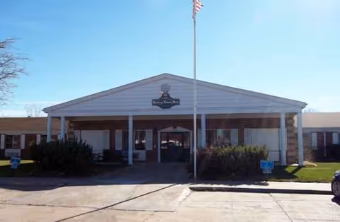 Exterior view of Bertrand Nursing Home Assisted entrance with a covered driveway and flagpole.