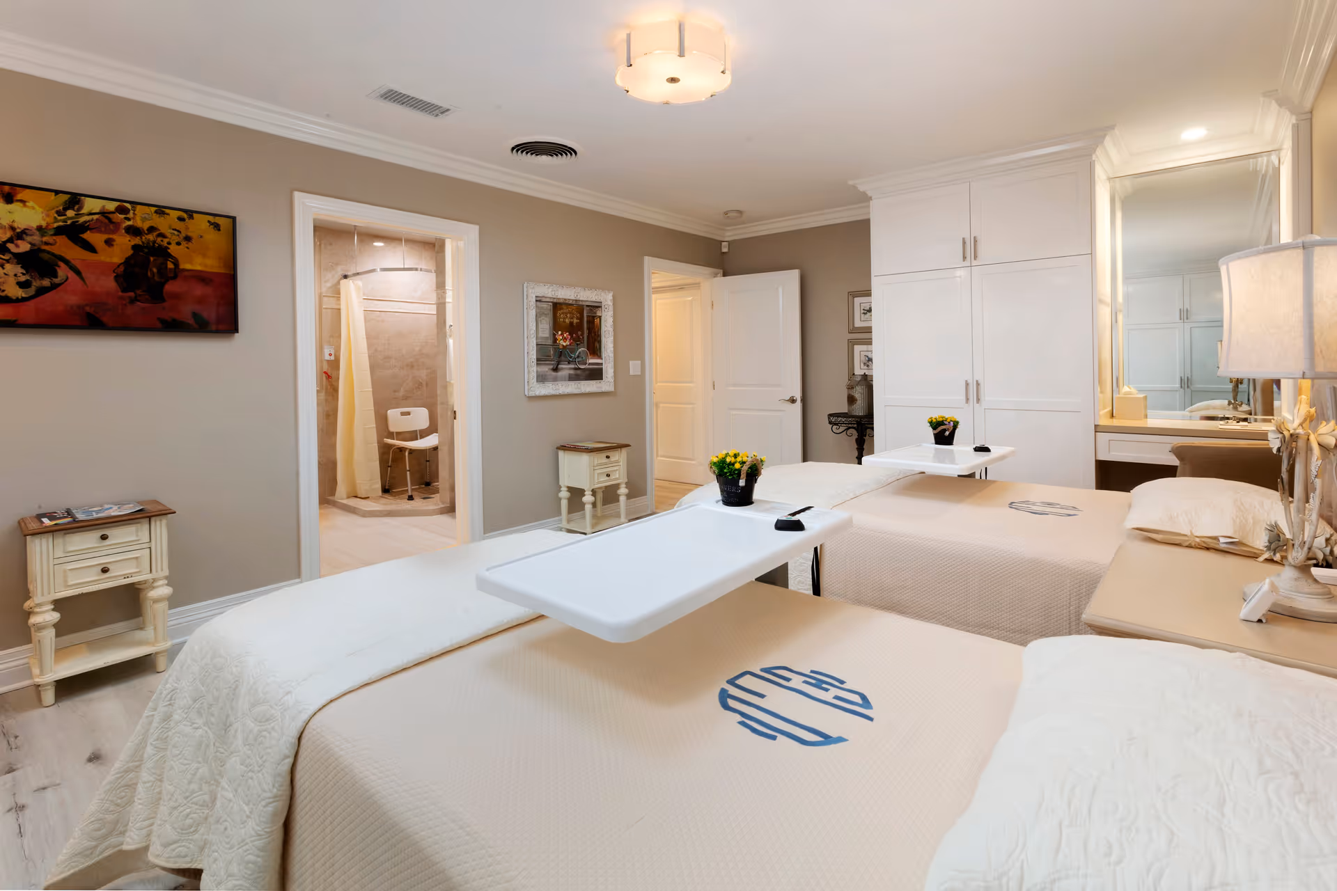 Shared bedroom with two beds, bedside tables, overhead light, and a view into an accessible bathroom.