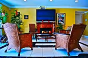 Cozy senior living lounge with wicker chairs, a fireplace, coffee table, and a mounted TV.