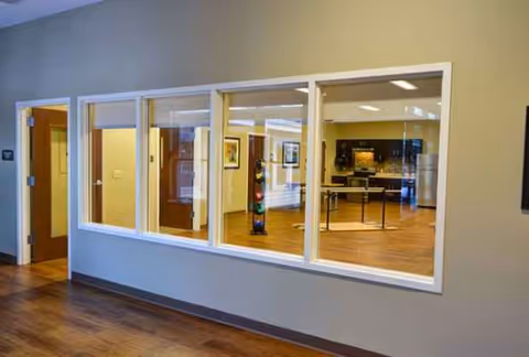 Interior corridor with a large windowed opening to a bright kitchen and dining area.