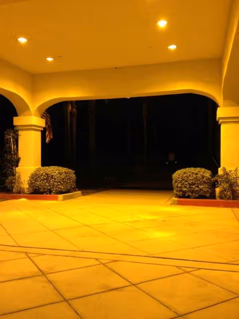 Night view of a covered building entrance with arches, columns, and warm outdoor lighting.