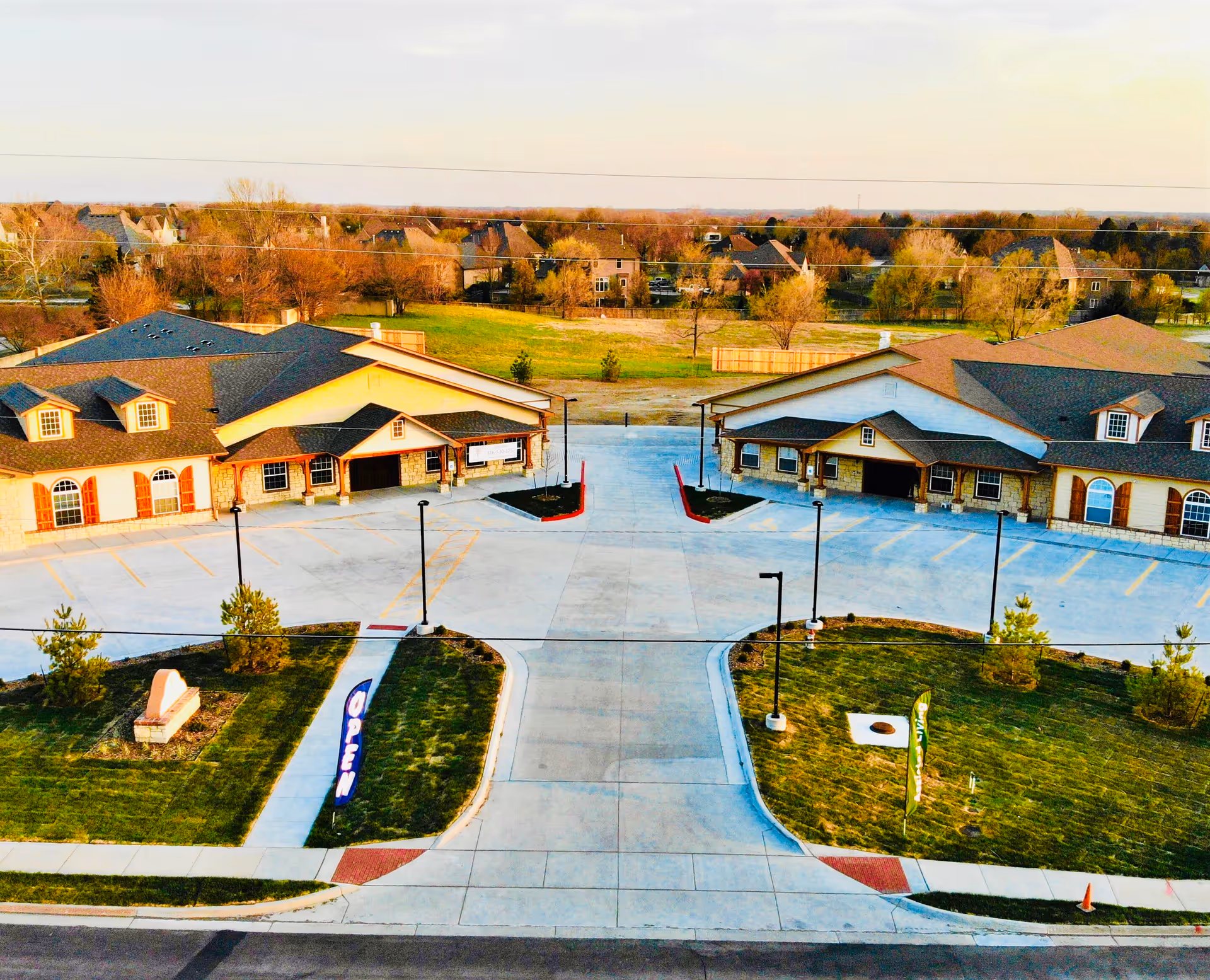 Aerial view of two single-story assisted living buildings facing a central driveway, parking area, and landscaped lawns with signage.