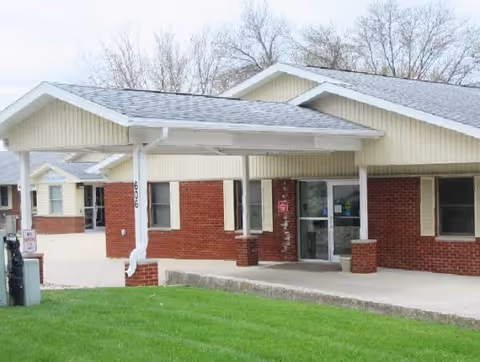 Brick facility exterior with covered entrance and manicured lawn.