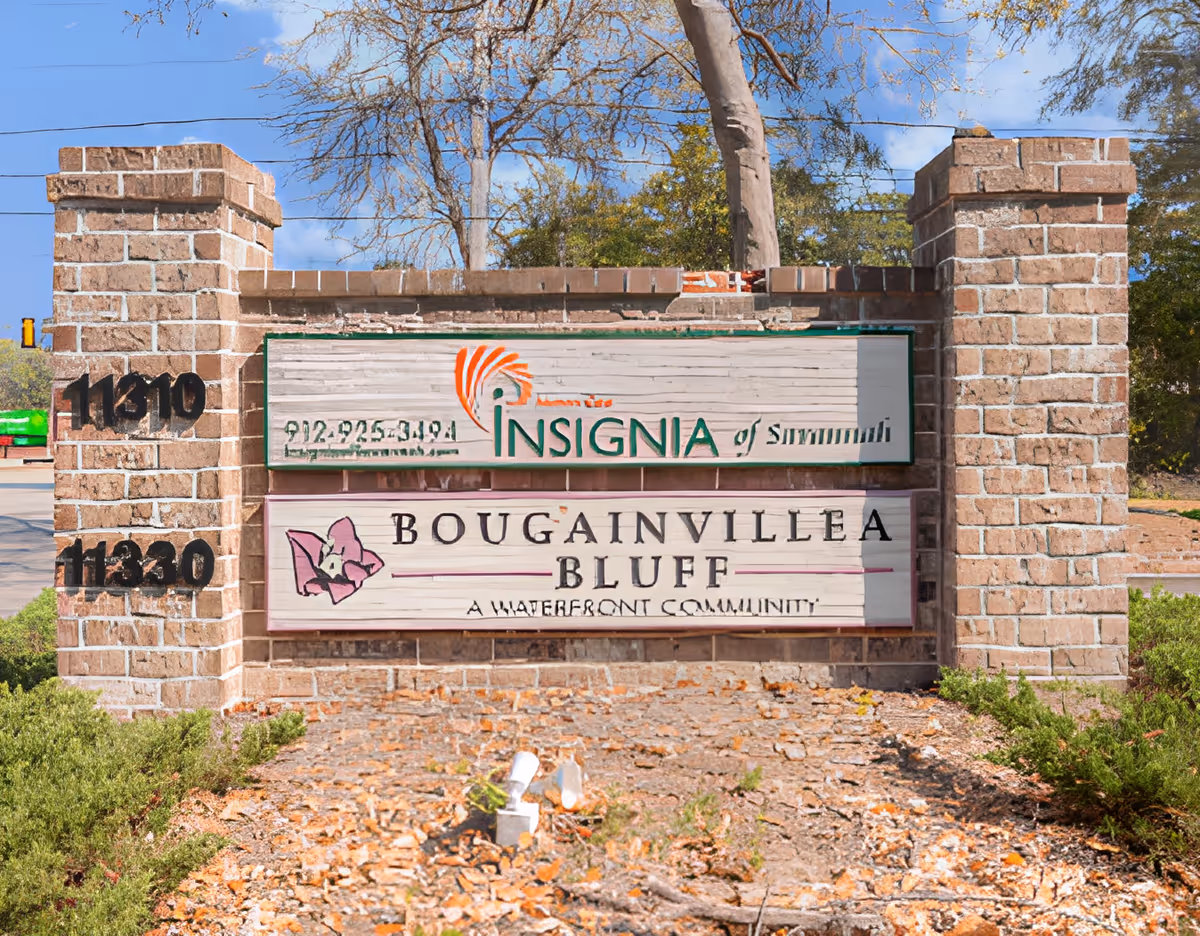 Brick entrance sign for Insignia of Savannah and Bougainvillea Bluff, a waterfront community, with trees and a clear blue sky in the background.