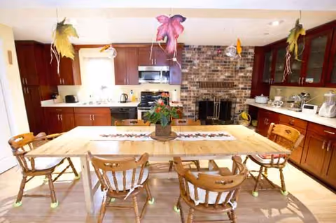 Bright kitchen and dining area featuring a large wooden table and brick fireplace.