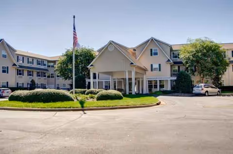 Exterior view of Lake Wylie Assisted Living & Memory Care with flagpole and landscaped circular island.