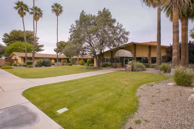 Front entrance of a single-story rehabilitation center with a manicured lawn, palm trees, and a covered entryway.