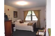 Small bedroom with a single bed, dresser, nightstand, and a curtained window.
