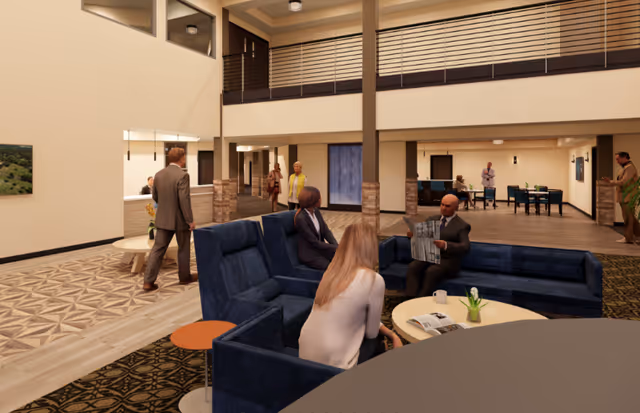 Two-story interior lounge with blue sofas and people seated and walking beneath an upper balcony.