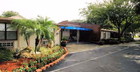 Exterior view of Lake Ridge Village front entrance with landscaping and a blue awning.