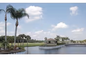 Outdoor lakeside view with palm trees, a pavilion, and a curved boardwalk.