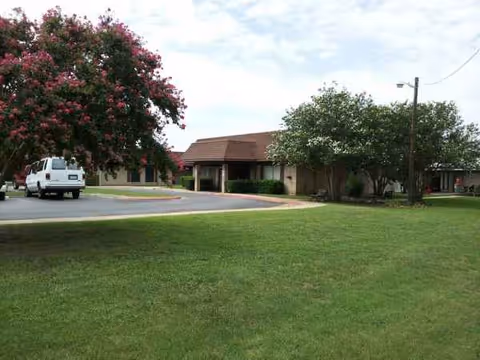 Exterior view of Seven Oaks Nursing and Rehabilitation with driveway, lawn, trees, and entrance canopy.