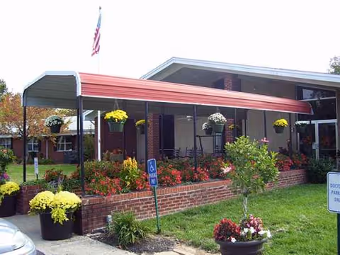 Front entrance of Christian Care Center of Kuttawa with red canopy and flowering planters