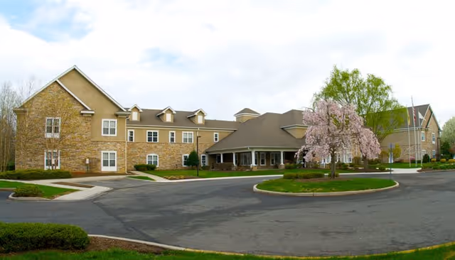 Exterior view of CareOne at Hamilton Assisted Living building with driveway and landscaped grounds.