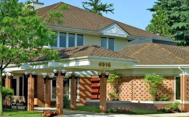 Front view of Malta House senior living facility with brick columns and greenery.