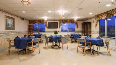 Empty dining room at Rossville Rehabilitation and Healthcare Center with blue tablecloths and flowers.