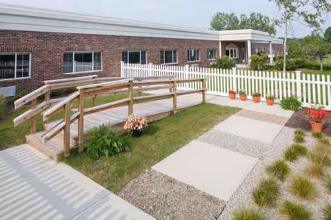 Exterior view of Elaine Center at Hadley showing a brick building, wooden ramp, and landscaped walkway.