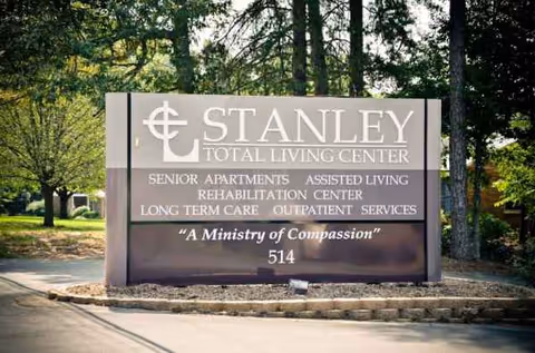 Outdoor sign reads Stanley Total Living Center with surrounding trees and landscaping.