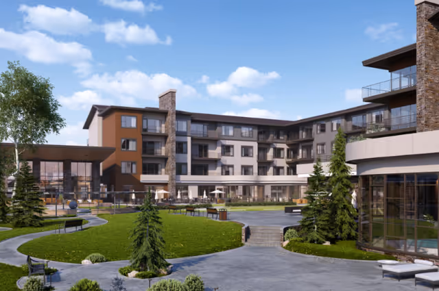 Outdoor view of The Ridge Pinehurst senior living facility showing a multi-story building with balconies, surrounded by landscaped gardens, walking paths, benches, and small trees under a partly cloudy sky.