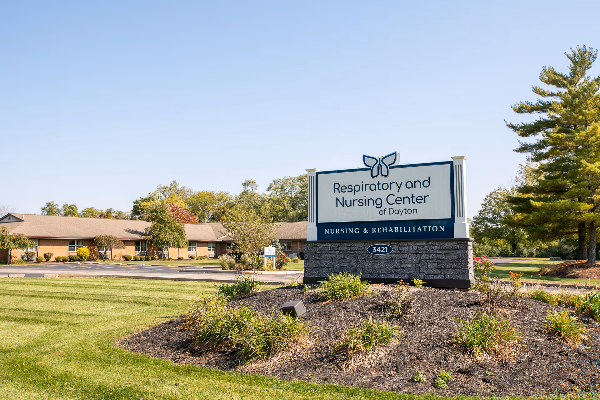 Exterior view of the Respiratory and Nursing Center of Dayton sign on a landscaped lawn with the facility building in the background.